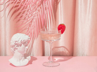 Summer creative layout with David head statue, cocktail glass and palm leaves with pastel pink curtain background. 80s or 90s retro aesthetic idea. Minimal summer fashion idea.
