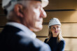 © Westend61 - Businesswoman wearing hard hat with businessman in factory