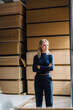 © Westend61 - Thoughtful businesswoman with arms crossed in front of stacked wood