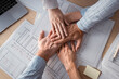 © Westend61 - Business people stacking hands on desk with architectural plans