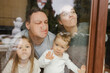 © Westend61 - Family pressing noses against window in house