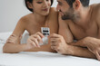 © chachamp - Happy young Asia woman and caucasian boyfriend in underwear holding condom at bedroom