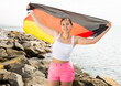 Happy woman on sea beach with Germany flag on a sunny day