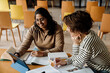 © Drobot Dean - Two cheerful female students studying together in college library