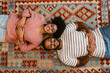 © Drobot Dean - Top view of young couple smiling while laying on carpet at home