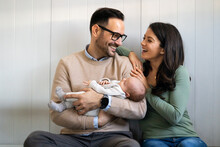 Portrait Of Parents And Newborn Baby. Father And Mother Kiss And Hug A Beautiful Newborn Child. .