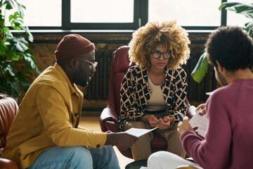 Leinwandbilder - Young serious African American businesswoman looking at one of male colleagues during discussion of financial data at working meeting