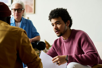 Poster - Young confident multi-ethnic businessman with financial document looking at African American male colleague during discussion