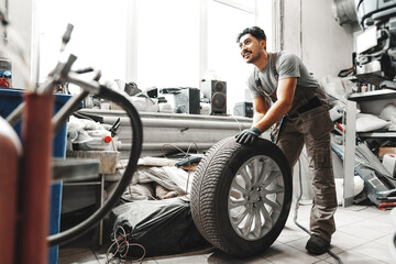 Wall Mural - Mechanic pushing a car tire in car service