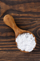 Wall Mural - White powdered tapioca starch in a wooden spoon, dry cassava root.