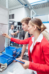 Wall Mural - Worker and manager on factory floor discussing product specifications looking at a plan sheet