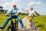 Fototapeta  - Seniors having fun on bicycles in spring landscape