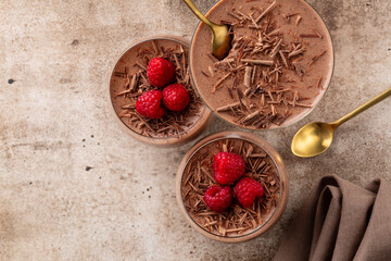 Sticker - Flat lay with chocolate mousse or pudding decorated with raspberries and dark chocolate sprinkles in portion glasses. Brown table. Copy space.