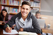 © Tasneem H/peopleimages.com - Learning, writing and college with portrait of man in library for education, research and classroom quiz. Focus, study and notebook with student at university for knowledge, scholarship and project