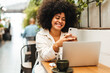 © (JLco) Julia Amaral - Woman with Afro hair sits in a cafe, reading a text message on her smartphone