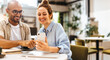 © (JLco) Julia Amaral - Happy colleagues using a mobile phone while working together in a cafe