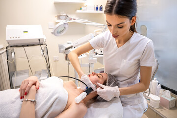 Wall Mural - Female patient receiving rejuvenation procedure performed by a professional beautician in a beauty clinic