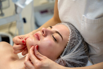 Wall Mural - Close up of beautiful young woman getting a face massage treatment at beauty clinic.