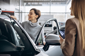 Wall Mural - Woman in car showroom talking to salesperson