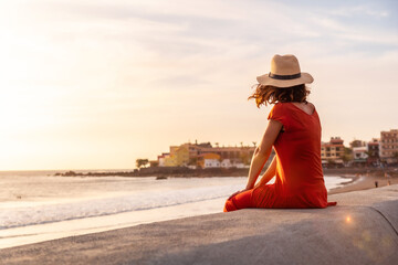 Wall Mural - Tourist woman at sunset enjoying vacations on the beach of Valle Gran Rey village in La Gomera, Canary Islands. Sitting looking at the sea