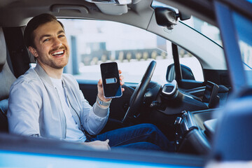 Man holding mobile phone with battery charged in his electric car