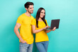 canvas print picture - Photo of two youngsters wearing yellow t-shirts denim jeans it specialists coworkers team communication netbook isolated on cyan color background