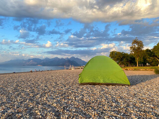 Family camping on the sea beach and mountains in the background, camping tent on the sea or ocean beach, independent tourism