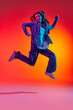 © Lustre Art Group  - Portrait of emotive, young girl wearing casual clothes jumping in air over red color studio background in neon light. Levitating dreamer