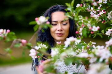 Wall Mural - portrait of a beautiful brunette woman in a blossoming apple orchard