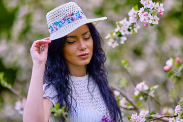 Wall Mural - portrait of a beautiful brunette woman in a blossoming apple orchard