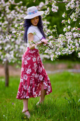 Wall Mural - portrait of a beautiful brunette woman in a blossoming apple orchard