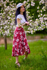 Wall Mural - portrait of a beautiful brunette woman in a blossoming apple orchard