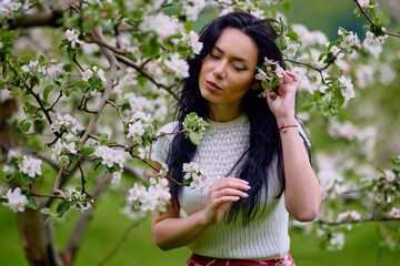 Wall Mural - portrait of a beautiful brunette woman in a blossoming apple orchard