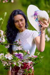 Wall Mural - portrait of a beautiful brunette woman in a blossoming apple orchard