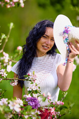 Wall Mural - portrait of a beautiful brunette woman in a blossoming apple orchard