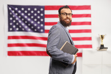 Poster - Bearded man with glasses holding books in front of USA flag