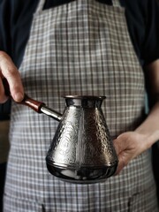 Woman holds a Copper Turk in her hands. Cezve in the Person Hand. Vintage Coffee Maker. Vertical poster for Coffee Shop.