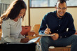 © Flamingo Images - Two African American businesspeople laughing together during an office meeting