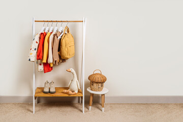 Wall Mural - Clothing Rack with kids outfits and storage baskets in children's room. Fashion clothes in autumn colors on hangers in wardrobe. Set of kids clothes and accessories. Montessori Clothing Rack.