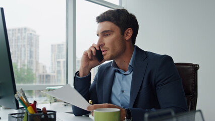 Nervous manager talking phone at glass workplace. Angry man throwing papers