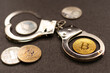 The concept of violation of the law in the crypto-currency sphere or hacker attack. Against the background of the yellow computer electronics board is a real bitcoin coin on police steel handcuffs