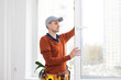 © Angelov - Workman in overalls installing or adjusting plastic windows in the living room at home