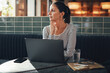 © Flamingo Images - Young businesswoman sitting at a table thinking about work