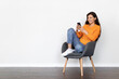 © Prostock-studio - Relaxed young woman chilling in armchair, using cell phone