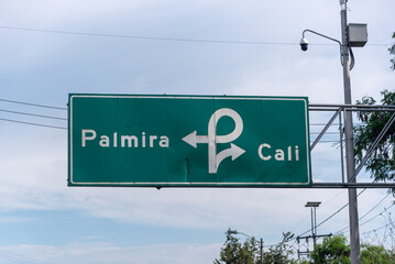 Wall Mural - Road sign with indication to Cali with security camera in the background. Colombia.