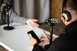 © Богдан Ємець - People in headphones recording a live podcast interview with a microphone in the studio holding a phone