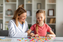 Child Development Specialist Working With Cute Little Girl During Lesson At Office