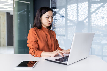 young asian female programmer, developer, tester is focused and serious sitting in the office and wo