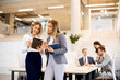 © BGStock72 - Two young business women looking at financial results on digital tablet in front of their team at the office