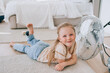 © Iona - Pretty cheerful little girl in casual laying on floor at bedroom close to fan at hot summer day chilling at home. Happy preschooler enjoying holiday home. Leisure, rest, childhood. Girls.